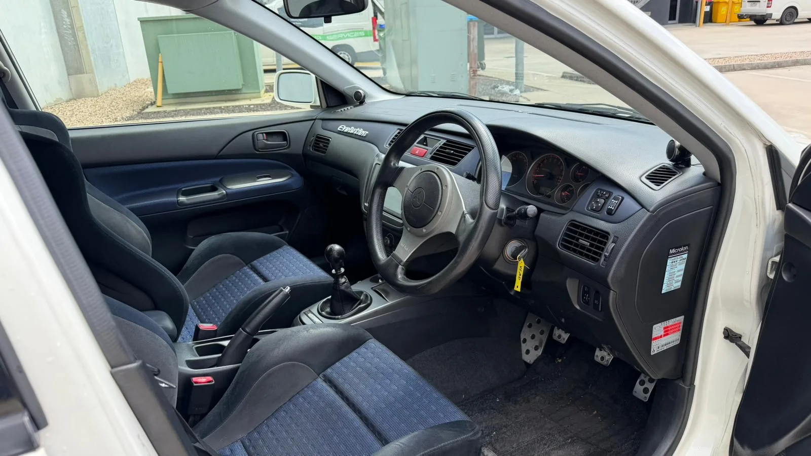 Interior of a Mitsubishi Evolution VIII GSR showing the factory manual gearbox and Evolution-branded dash