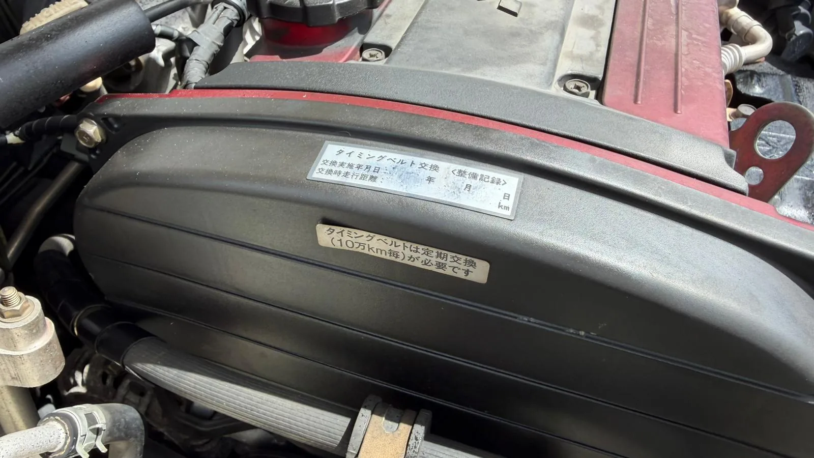 Timing belt service interval sticker inside the engine bay of a Japanese-market Evolution VIII