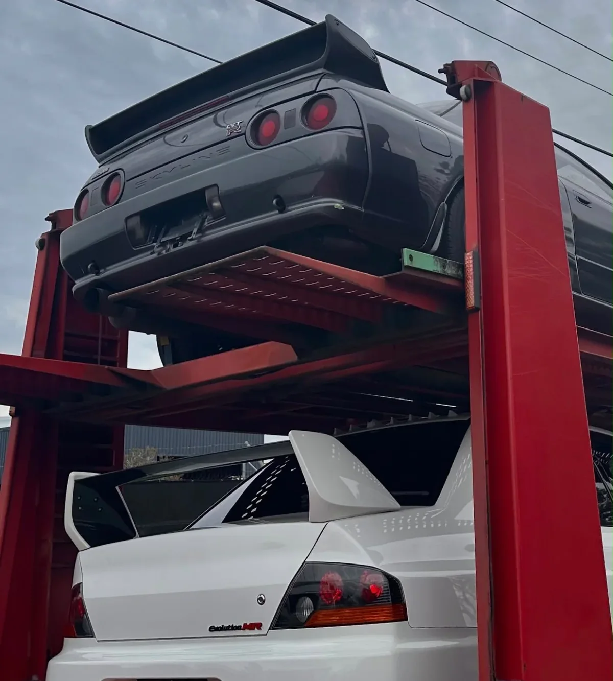 Nissan Skyline R32 GT-R and white Mitsubishi Lancer Evolution MR loaded on a car carrier